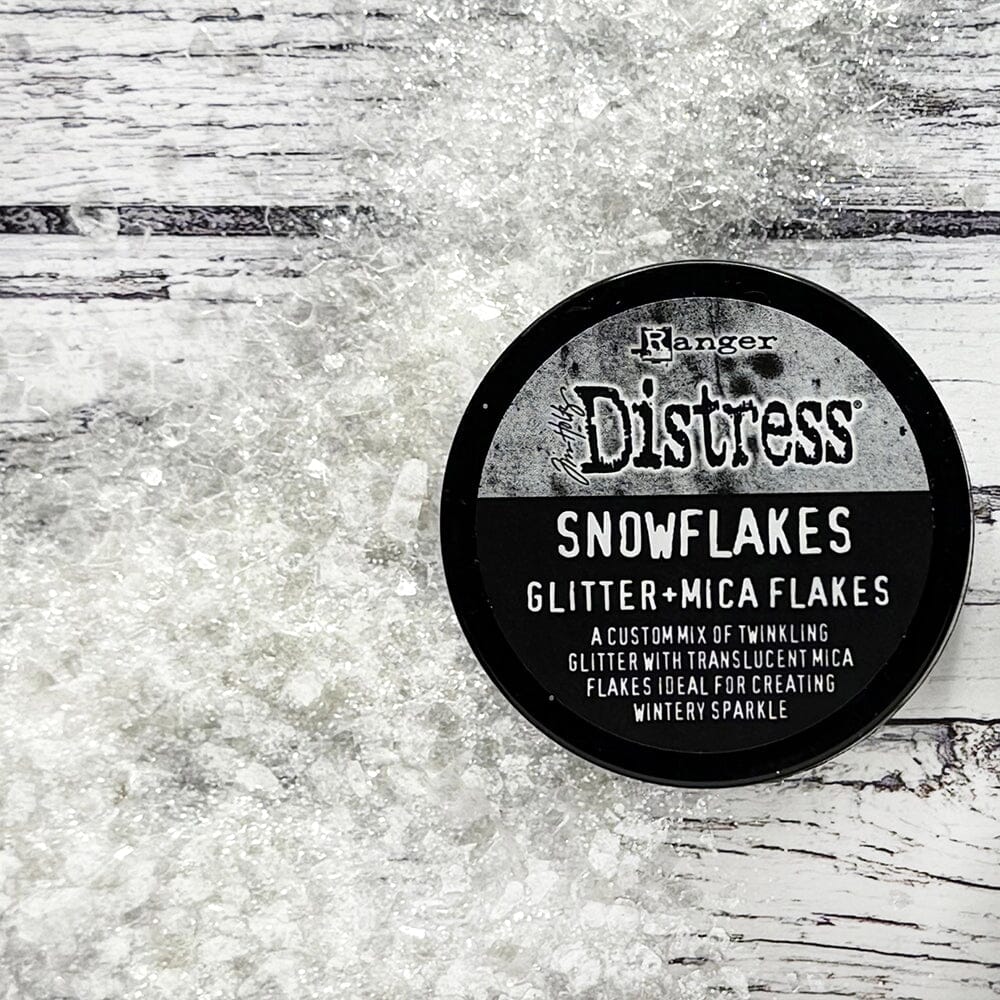 Snowflakes - Mica Flakes and Sparkly Dry Glitter ... by Tim Holtz Distress and Ranger. 3fl oz (88.7ml) jar. Made by Ranger. Tim Holtz Distress® Snowflakes combines a custom mix of twinkling glitter with translucent mica flakes for a nostalgic wintery sparkle. Adhere Snowflakes with Distress Collage Medium, Ranger Glossy Accents, or other liquid adhesives. Photo from Ranger showing the contents on a wooden backdrop.