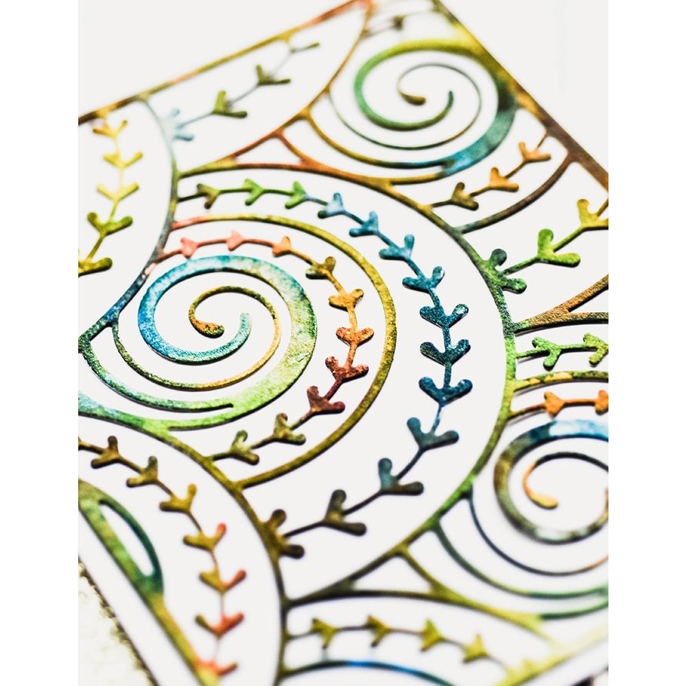 Curlicue Plate - Die Cutting Template by Memory Box (no. MB94698). Spirals and arrows curling and overlapping. Design size 4" x 5 1/4" (10.2cm x 13.3cm). 1 (one) template. This gorgeous design features overlapping spirals of curls and arrows in fine lines, perfect for layering and adding dimension for cards, scrapbook pages, journaling, mixed media of all kinds. Photo of a closeup of the rustic rainbow coloured cutout.