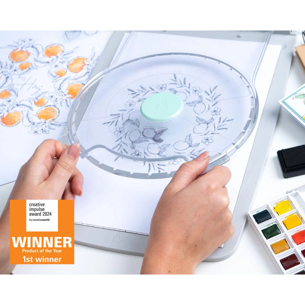 Stamp and Spin Tool ... Sizzix Studio Mixed Media. For precision alignment and repetitive layering of stamps to produce repeating circular designs in mixed media, papercrafts, scrapbooking, art journaling, visual arts of all kinds. This award winning adapter for the Sizzix Stamping Platform system will enable you to create circular artwork, wreaths, rings, repeating areas of design in different angles. Features 8 inch wide circular workarea, transparent lid for easy placement. Example of use.