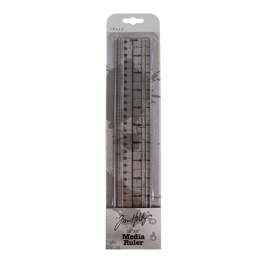 Media Ruler ... by Tim Holtz and Tonic Studios. Clear plastic ruler with precise measurements in both metric and imperial, dual steel cutting edges, non-slip backing, 2" wide and 12" long. Photo showing the ruler inside the boxed packaging.