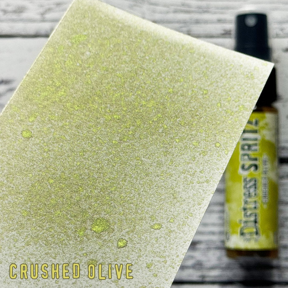 Crushed Olive - Distress Spritz by Tim Holtz and Ranger - a pearlised fusion of colourful mica pigment and clear medium to easily create a gorgeous shimmery splattery effect on artwork in colours that compliment the whole Distress rainbow. Each bottle contains 1 fl oz (29ml) with a fine spritzing nozzle and easy to hold container. Use Tim Holtz Distress Spritz for mixed media, scrapbooking, papercrafts, cardmaking, junk journals and visual arts. Photo is a sample by Ranger.