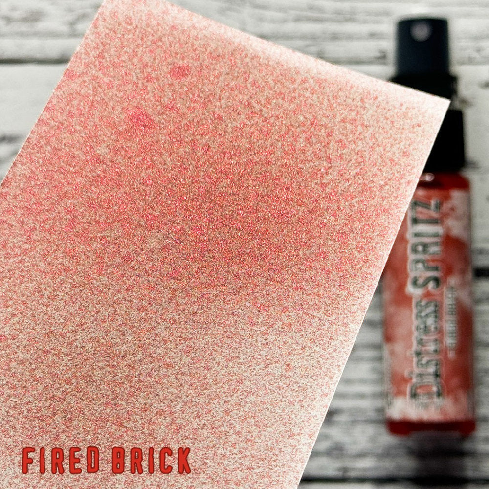 Fired Brick - Distress Spritz by Tim Holtz and Ranger - a pearlised fusion of colourful mica pigment and clear medium to easily create a gorgeous shimmery splattery effect on artwork in colours that compliment the whole Distress rainbow. Each bottle contains 1 fl oz (29ml) with a fine spritzing nozzle and easy to hold container. Use Tim Holtz Distress Spritz for mixed media, scrapbooking, papercrafts, cardmaking, junk journals and visual arts. Photo is a sample by Ranger.