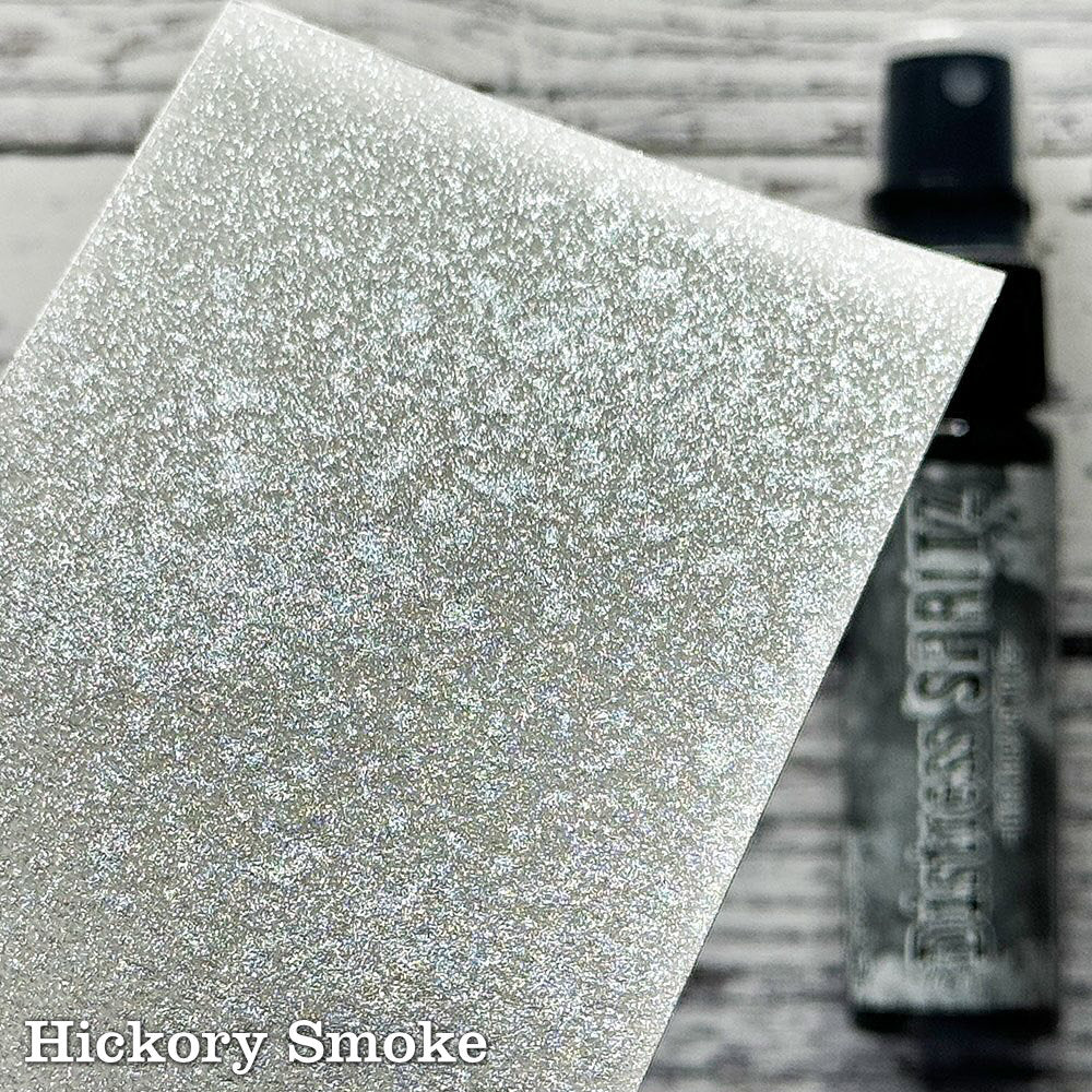 Hickory Smoke - Distress Spritz by Tim Holtz and Ranger - a pearlised fusion of colourful mica pigment and clear medium to easily create a gorgeous shimmery splattery effect on artwork in colours that compliment the whole Distress rainbow. Each bottle contains 1 fl oz (29ml) with a fine spritzing nozzle and easy to hold container. Use Tim Holtz Distress Spritz for mixed media, scrapbooking, paper crafts, card making, junk journals and visual arts. Photo is a sample by Ranger.