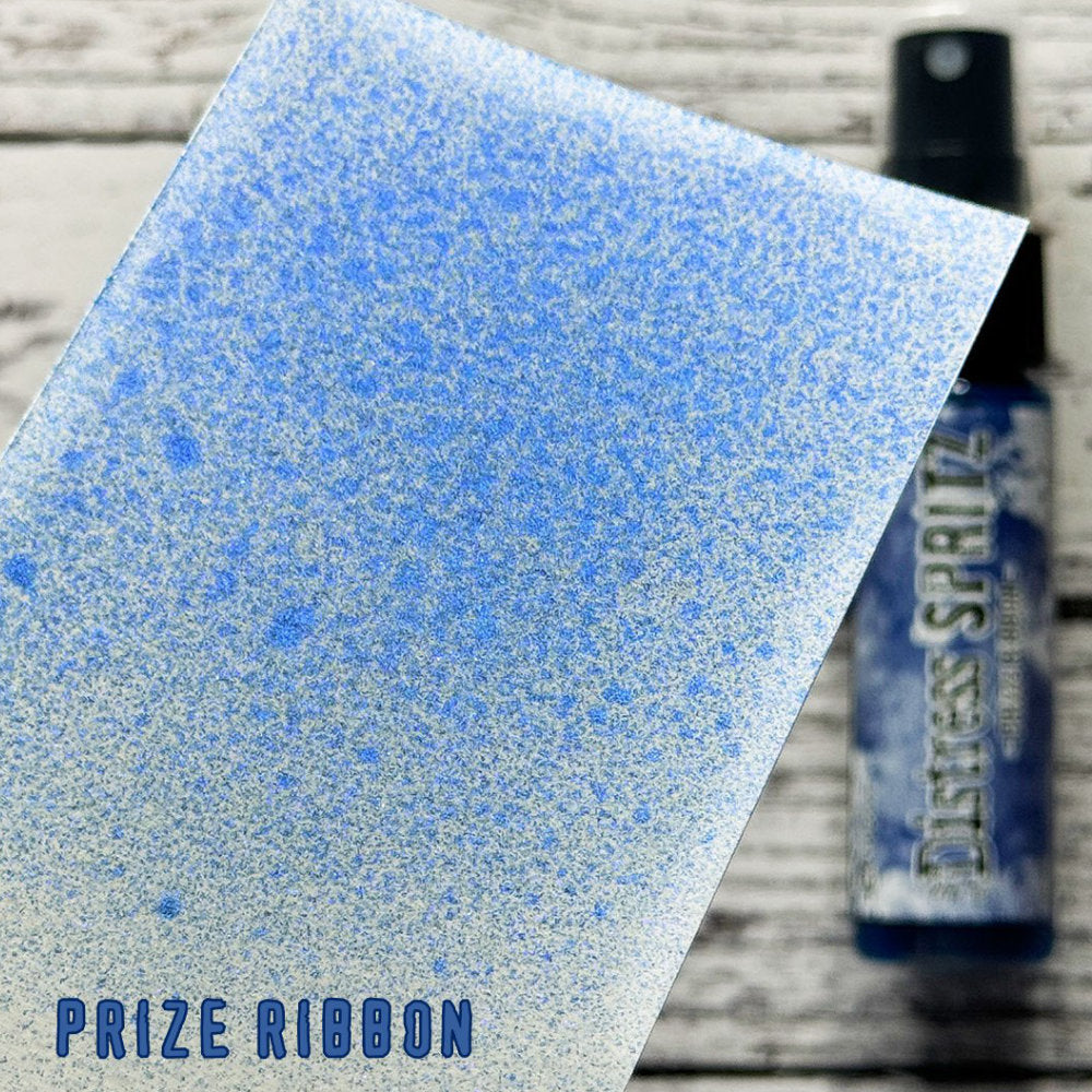 Prize Ribbon - Distress Spritz by Tim Holtz and Ranger - a pearlised fusion of colourful mica pigment and clear medium to easily create a gorgeous shimmery splattery effect on artwork in colours that compliment the whole Distress rainbow. Each bottle contains 1 fl oz (29ml) with a fine spritzing nozzle and easy to hold container. Use Tim Holtz Distress Spritz for mixed media, scrapbooking, papercrafts, cardmaking, junk journals and visual arts. Photo is a sample by Ranger.