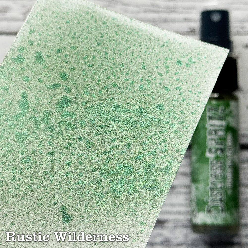 Rustic Wilderness - Distress Spritz by Tim Holtz and Ranger - a pearlised fusion of colourful mica pigment and clear medium to easily create a gorgeous shimmery splattery effect on artwork in colours that compliment the whole Distress rainbow. Each bottle contains 1 fl oz (29ml) with a fine spritzing nozzle and easy to hold container. Use Tim Holtz Distress Spritz for mixed media, scrapbooking, paper crafts, card making, junk journals and visual arts. Photo is a sample by Ranger.