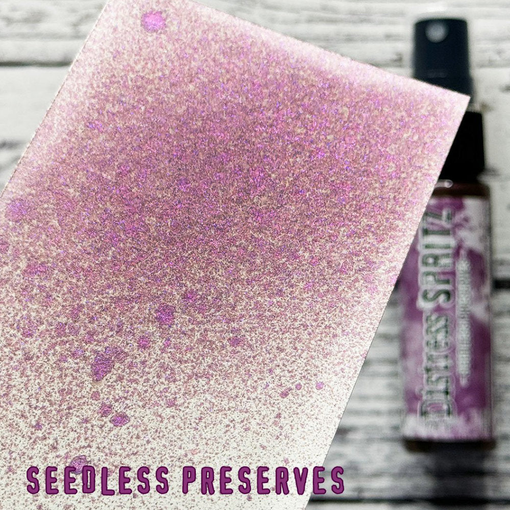 Seedless Preserves - Distress Spritz by Tim Holtz and Ranger - a pearlised fusion of colourful mica pigment and clear medium to easily create a gorgeous shimmery splattery effect on artwork in colours that compliment the whole Distress rainbow. Each bottle contains 1 fl oz (29ml) with a fine spritzing nozzle and easy to hold container. Use Tim Holtz Distress Spritz for mixed media, scrapbooking, papercrafts, cardmaking, junk journals and visual arts. Photo is a sample by Ranger.
