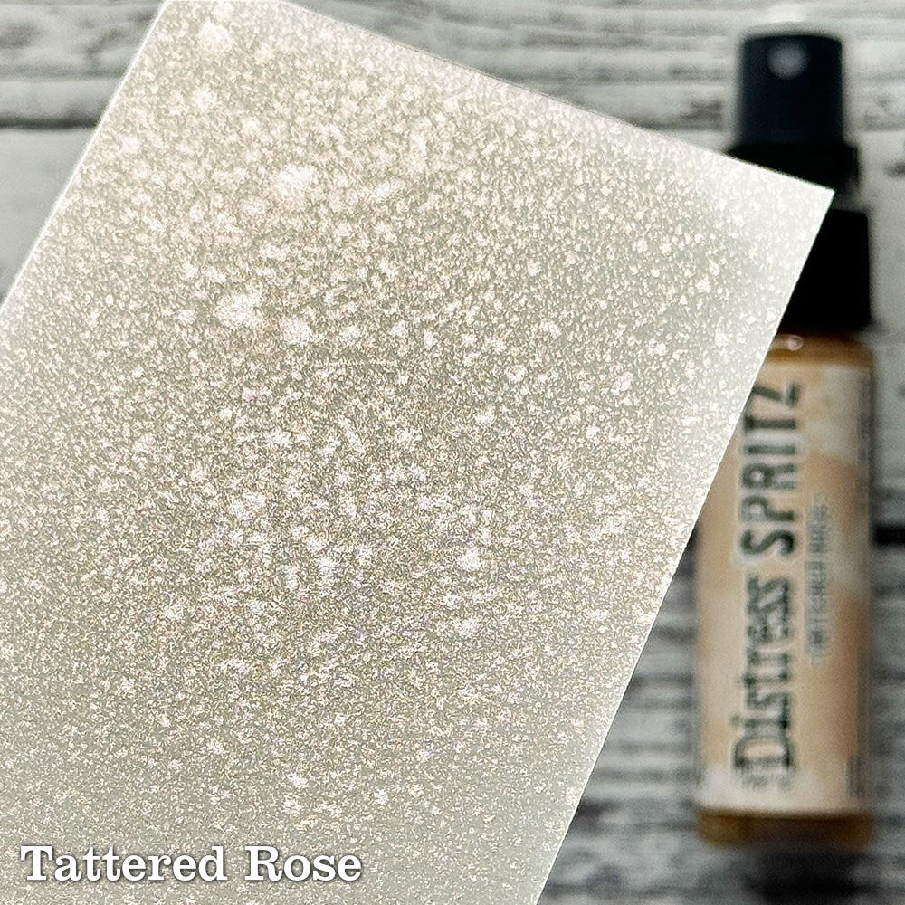 Tattered Rose - Distress Spritz by Tim Holtz and Ranger - a pearlised fusion of colourful mica pigment and clear medium to easily create a gorgeous shimmery splattery effect on artwork in colours that compliment the whole Distress rainbow. Each bottle contains 1 fl oz (29ml) with a fine spritzing nozzle and easy to hold container. Use Tim Holtz Distress Spritz for mixed media, scrapbooking, paper crafts, card making, junk journals and visual arts. Photo is a sample by Ranger.