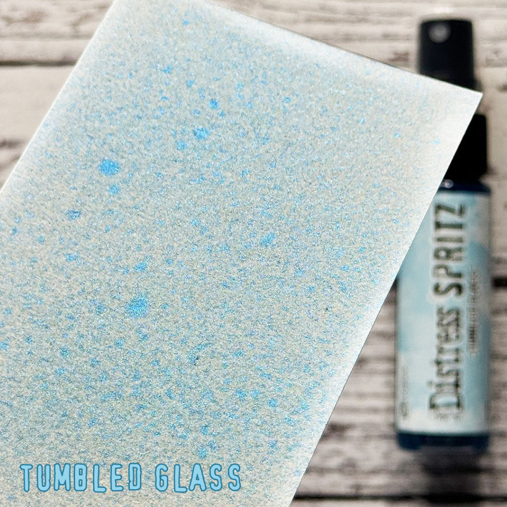 Tumbled Glass - Distress Spritz by Tim Holtz and Ranger - a pearlised fusion of colourful mica pigment and clear medium to easily create a gorgeous shimmery splattery effect on artwork in colours that compliment the whole Distress rainbow. Each bottle contains 1 fl oz (29ml) with a fine spritzing nozzle and easy to hold container. Use Tim Holtz Distress Spritz for mixed media, scrapbooking, papercrafts, cardmaking, junk journals and visual arts. Photo is a sample by Ranger.