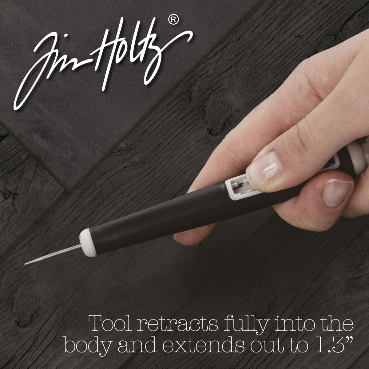 Retractable Craft Pick - by Tim Holtz and Tonic Studios ... this is a 5" long visual arts tool with a black Kushgrip rubber handle, hanging loop and easy to use switch. Use the long steel point for poking holes, lifting layers, clearing nozzles, extends up to 1.25 inches and holds safely in place at various depths. Photo from Tonic Studios, showing in use.