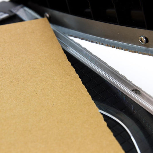 close up photo of Deckle Blade Trimmer by Tim Holtz and Tonic Studio. Tim Holtz Deckle (Torn Edge) Blade Guillotine Paper Cutter - with a unique torn edge style blade, ergonomic comfort Kushgrip handle. Use to create the look of rugged torn edges to paper and cardboard easily and quickly. Made by Tonic Studio with precision ground, ultra sharp blade with a rough ragged pattern, this strong trimmer is built to last.