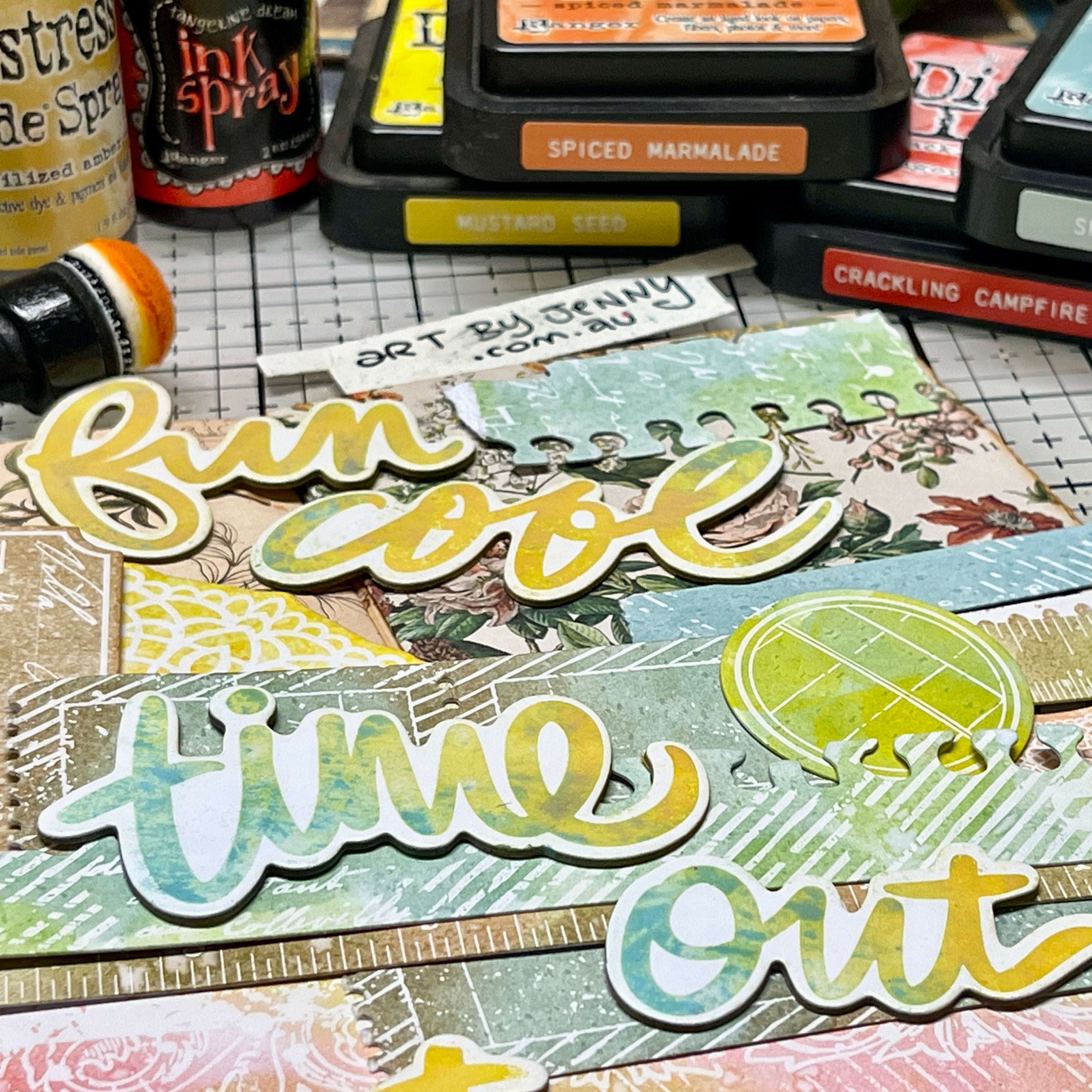 A close up photograph by Jenny James showing the 49 and Market paper embellishments called 'Irresistable' die cuts by Vicki Boutin. This photo shows the 'chipboard words' with strips from 'die cut borders', coloured using Distress and Dylusions inks to create customised scrapbooking layers for arts and crafts.