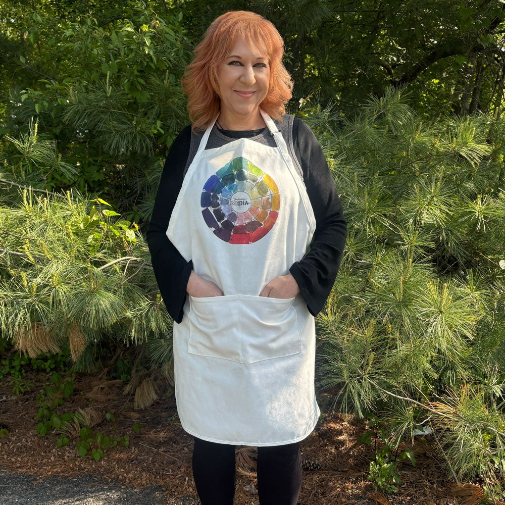 Apron ... by Dina Wakley MEdia and Ranger - Large adult sized apron made of natural warm white canvas material 28" wide x 32" long, with adjustable neck strap, long ties and two large pockets, each 7 1/8" wide x 7" deep.

The printed design at the neckline is of a colour theory wheel featuring beautiful colourful realistic looking paint marks over black outlines with Dina's logo in the centre.