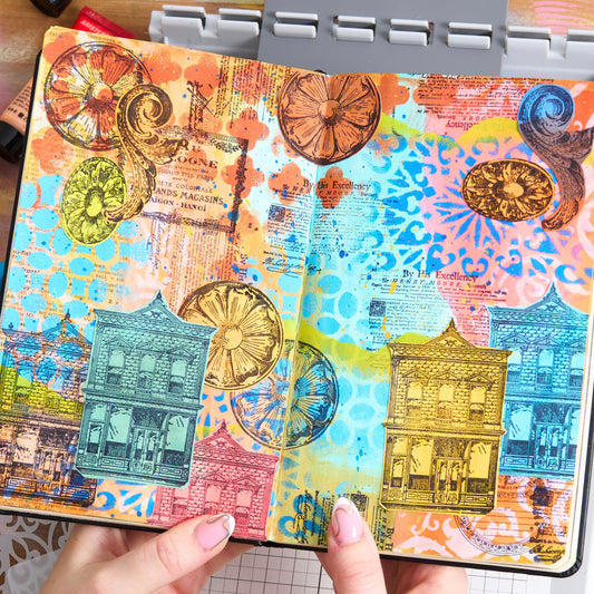 sample of Build It - Stencils and Stamps ... Sizzix Studio Mixed Media Kit ... by Mark Montano and Sizzix. Layering art stencils and clear acrylic stamps to use for mixed media, papercrafts, art journaling, visual arts of all kinds. Pack has 7 (seven) stamp designs and 3 (three) stencils, 6 3/4" x 10" in size.

The stamp designs in this set include a Royal notice, vintage round label, floral round and oval plaster cast, simple scroll, eau de cologne advert, double storey brick building with shopfront window