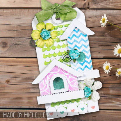 Birdhouse Ornaments - Thickboard Shapes by Stampers Anonymous. 2 (two) sheets of compressed board with precut designs of little bird house pieces, ready to pop out and use to create 4 (four) house faces, 2 short and 2 tall. 18 pieces per sheet. ORN01  Each sheet is 4 1/2" x 6 3/4" and approx 2mm thick. Photograph of a birdhouse tag by Michelle P, made using paints, flowers, stencils and ribbons.