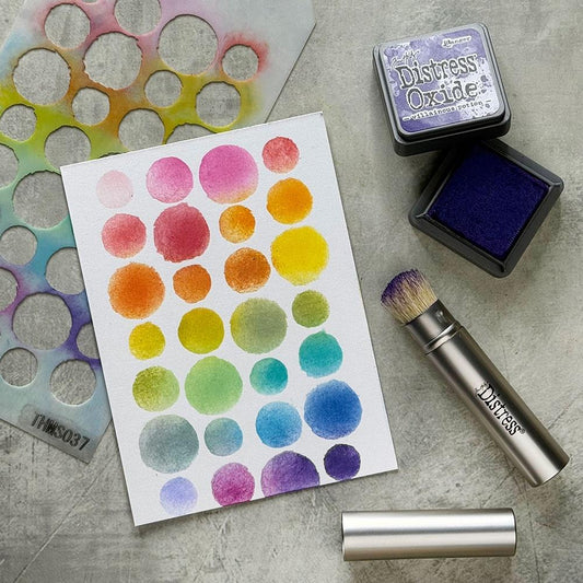 Mini Distress Blending Brush (3 pack) ... by Tim Holtz. Natural bristle brush with retractable silver coloured casing and lid. 3 (three) brushes.

Tim's fantastic retractable blending brush has been miniaturised for those smaller projects, finer details and intricate patterns on stencils, embossing folders, stamps and more.

The photo by Tim Holtz shows a stencil, paper spotted with oxide colour together with  Distress Mini Oxide Ink Pad (Villainous Potion, purple) and one brush with the lid off. 