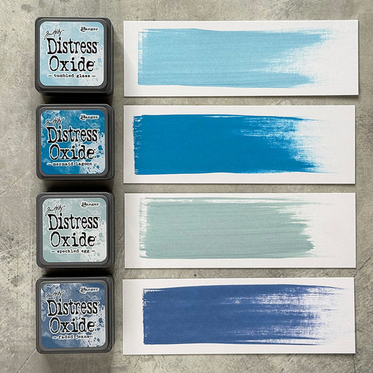 Mini Distress Oxide Ink Pads - Set 10 - by Tim Holtz and Ranger ... featuring water-reactive dye and pigment ink fusion that creates an oxidised effect when spattered, stamped, brushed and or sprayed with water. The colours are opaque and dry with a soft matte finish. Set of 4 (four) colours in Mini Ink Pad Cubes with 1" square raised felt, one of each (TDIK91561).

Colours in this set are ...
- Speckled Egg
- Tumbled Glass
- Mermaid Lagoon
- Faded Jeans
... one of each colour. Photograph example