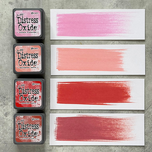 Mini Distress Oxide Ink Pads - Set 7 - by Tim Holtz and Ranger ... featuring water-reactive dye and pigment ink fusion that creates an oxidised effect when spattered, stamped, brushed and or sprayed with water. The colours are opaque and dry with a soft matte finish. Set of 4 (four) colours in Mini Ink Pad Cubes with 1" square raised felt, one of each (TDIK91530).

Colours in this set are ...
- Kitsch Flamingo
- Saltwater Taffy
- Candied Apple
- Fired Brick
... one of each colour. Photo of swatched samples
