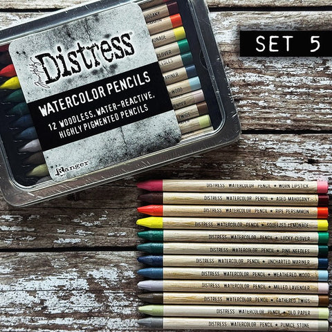 Woodless Watercolour Pencils in Distress colours, set 5 ... by Tim Holtz and Ranger. 12 (twelve) woodless watercolour pencils in Worn Lipstick, Aged Mahogany, Ripe Persimmon, Squeezed Lemonade, Lucky Clover, Pine Needles, Uncharted mariner, Weathered Wood, Milled Lavender, Gathered Twigs, Old Paper, Pumice Stone. One of each colour, approx 5" long. Photo showing a tin of pencils with 12 loose ones.