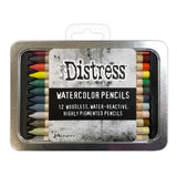 Woodless Watercolour Pencils in Distress colours, set 5 ... by Tim Holtz and Ranger. 12 (twelve) woodless watercolour pencils in Worn Lipstick, Aged Mahogany, Ripe Persimmon, Squeezed Lemonade, Lucky Clover, Pine Needles, Uncharted mariner, Weathered Wood, Milled Lavender, Gathered Twigs, Old Paper, Pumice Stone. One of each colour, approx 5" long. Photo of a closed tin of pencils with a label.