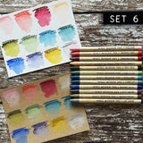 Woodless Watercolour Pencils in Distress colours, set 6 ... by Tim Holtz and Ranger. 12 (twelve) woodless watercolour pencils in Spun Sugar, Abandoned Coral, Lumberjack Plaid, Dried Marigold, Forest Moss, Bundled Sage, Broken China, Stormy Sky, Blueprint Sketch, Dusty Concord, Brushed Corduroy, Lost Shadow. One of each colour, approx 5" long. Photo showing swatched colours on watercolour paper and kraft stock.