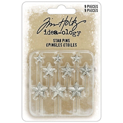 Star Pins, Christmas 2026 ... Idea-Ology Adornments by Tim Holtz. Beautifully made silver coloured sharp pins topped with 5-pointed stars, to use as embellishments for Christmas and other celebrations on display makes, dioramas, mixed media, paper crafts, mixed media and visual arts. 9 (nine) pins, 3 of each sized star. TH94498. Photo of the stars within packaging.
