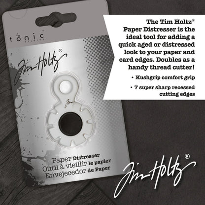 Paper Distresser - by Tim Holtz and Tonic Studios ... this is a tool for roughing up paper, cardstock edges and cutting threads in papercrafts, mixed media and tactile crafts. Includes a Kushgrip holder, hanging loop and 7 sharp recessed edges. Ergonomic Kushgrip round centre spot for comfort during handling, with very sharp steel blades recessed within the grey round plastic surround. It is safe to hold and easy to use. Photo from Tonic Studios of packaging.