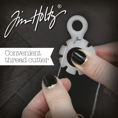 Paper Distresser - by Tim Holtz and Tonic Studios ... this is a tool for roughing up paper, cardstock edges and cutting threads in papercrafts, mixed media and tactile crafts. Includes a Kushgrip holder, hanging loop and 7 sharp recessed edges. Ergonomic Kushgrip round centre spot for comfort during handling, with very sharp steel blades recessed within the grey round plastic surround. It is safe to hold and easy to use. Photo from Tonic Studios of tool in use.