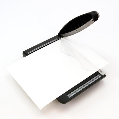 photograph with a sheet of white cardstock - Tim Holtz Deckle (Torn Edge) Blade Guillotine Paper Cutter - with a unique torn edge style blade, ergonomic comfort Kushgrip handle. Use to create the look of rugged torn edges to paper and cardboard easily and quickly. Made by Tonic Studio with precision ground, ultra sharp blade with a rough ragged pattern, this strong trimmer is built to last.