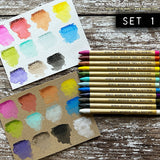 Distress Watercolour Pencils, set 1 ... by Tim Holtz. 12 (twelve) woodless watercolour pencils in Picked Raspberry, Fired Brick, Rusty Hinge, Mustard Seed, Peeled Paint, Salvaged Patina, Speckled Egg, Salty Ocean, Villainous Potion, Walnut Stain, Black Soot, Picket Fence. One of each colour shown on both kraft and watercolour paper.
